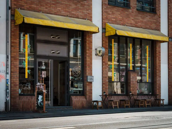 Das Café Nyanko in der Zschocherschen Straße in Leipzig-Plagwitz mit gelben Markisen und Außenbestuhlung.