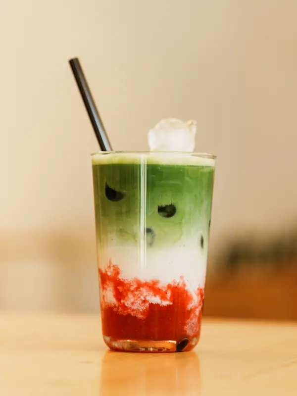 Strawberry Matcha Latte im Glas mit Erdbeerschicht, Milch und Matcha.